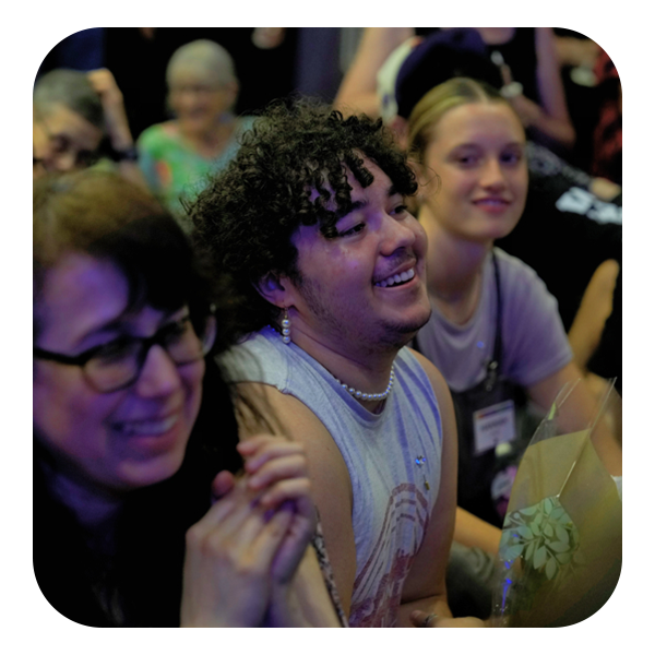 A gathering of people in a room, featuring one individual with a bright smile, enhancing the overall cheerful ambiance.