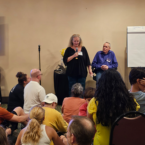 A group of individuals engaged in a seminar, listening attentively as a participant shares her personal experiences.