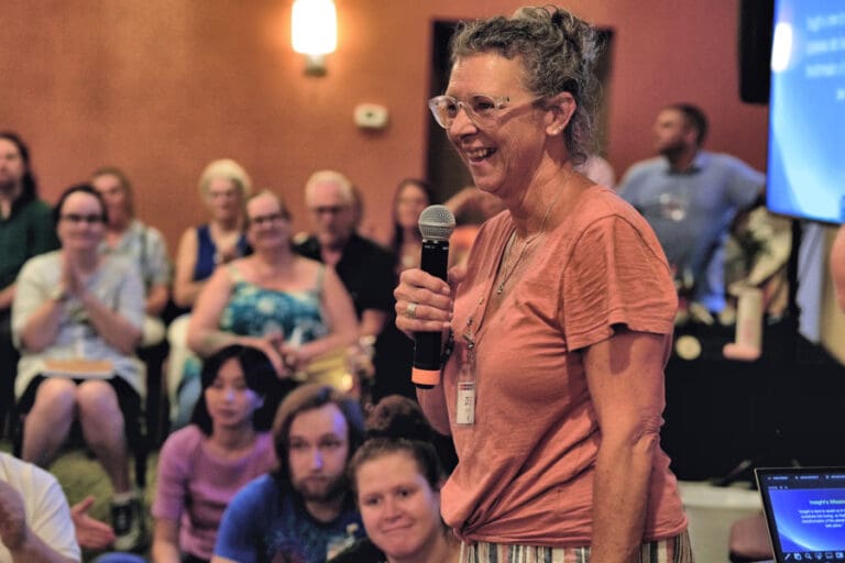 A woman delivers a speech into a microphone, captivating the attention of the crowd gathered before her.