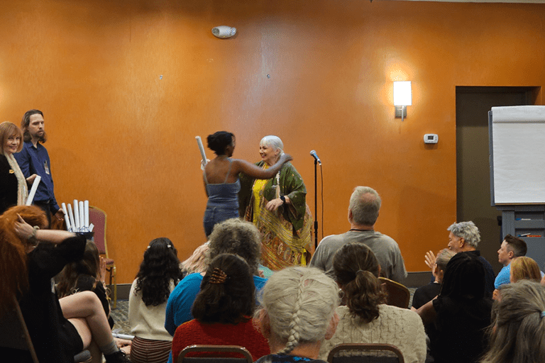 Several people gathered in a spacious room, sitting together while someone is delivering his speech during Insight II